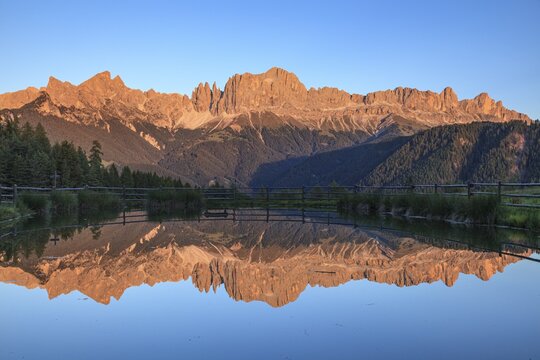 Mountains reflected in a small mountain lake, sunset, evening light, Wuhnleger, view of rose garden, Dolomites, South Tyrol, Italy