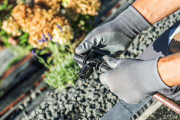 Gardener Works With Irrigation Tool Near Flowers