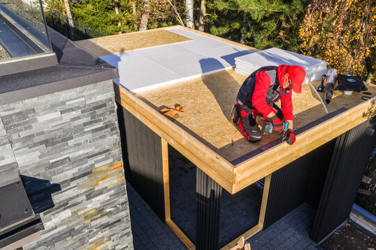 Construction Work on a Flat Roof Structure Near Trees