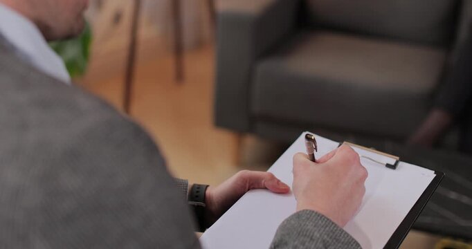Close up man therapist taking notes on papers at psychology session with unhappy woman, complaining about relationship problems. Counseling advisor writing report at therapy meeting.
