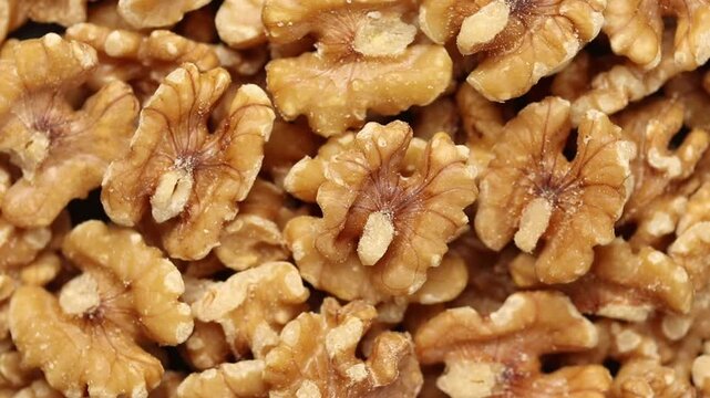 Pile of shelled and halved walnut kernels rotating for background. Top view shot