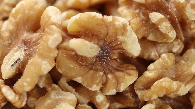 Pile of shelled and halved walnut kernels rotating. Close-up view