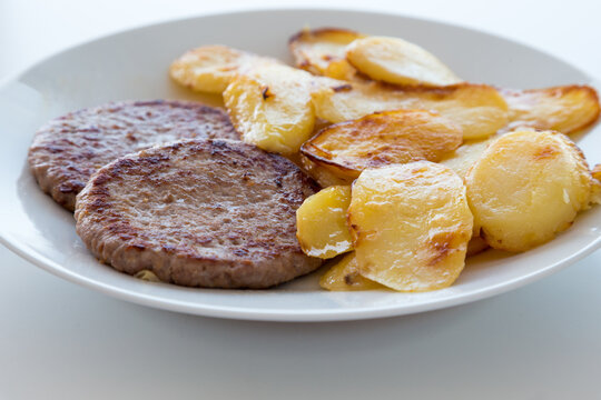 Hamburger e patate arrosto su piatto bianco