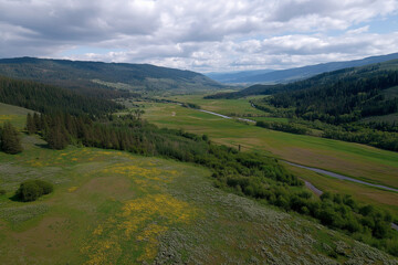 Naklejka premium A stunning aerial view of a lush green valley bordered by majestic mountains under a dramatic sky, capturing the essence of nature's beauty and serenity in a peaceful landscape.