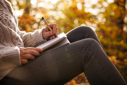 Woman writing diary outdoors. Closeup female hand with pen and notebook. Meditation through journaling