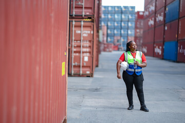 Obraz premium Tired African warehouse employee standing near cargo containers while drinking water, workforce endurance, logistics industry, daily labor routine, and physical demands of shipping operations.