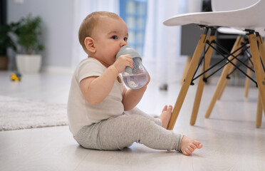 Obraz premium A baby is drinking from a bottle while sitting on the floor