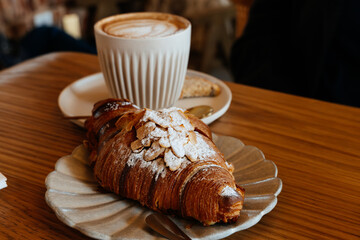 Delicious almond croissant with a latte in a cozy cafe setting