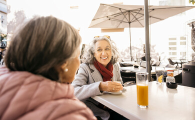 Senior women friends enjoying outdoor cafe conversation