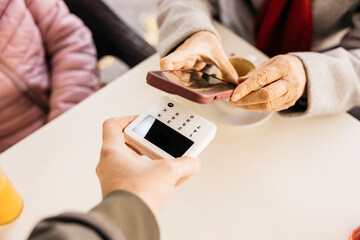 Senior woman making contactless mobile payment with smartphone