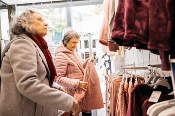 Senior women friends enjoying retail therapy shopping for clothes