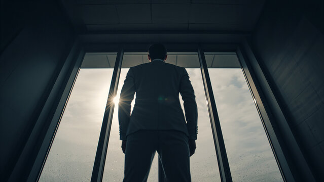 Vision of Success: Businessman Silhouetted Against a Bright Sky by a Large Window