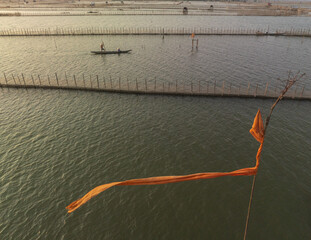 Aerial view of a solitary boat gently gliding through the reflective waterways, framed by the intricate network of fences, Chuon lagoon, Hue Province, Vietnam