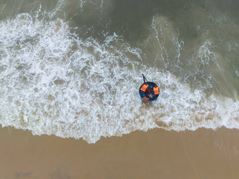 Aerial view of a boatman with his coracle as the waves crash against the shore, Tam Tien, Quang Nam, Vietnam