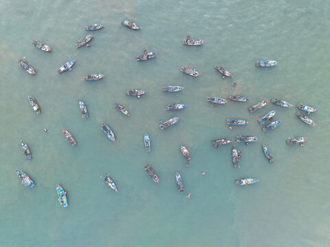 Aerial view of fishing boats scattered across the shimmering turquoise waters, their hulls casting faint shadows below, creating a mesmerizing dance of light and color.,Tam Tien, Quang Nam, Vietnam