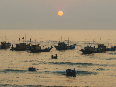 Aerial view of fishing boats bobbing gently on the water under the warm glow of the setting sun, Tam Tien, Quang Nam, Vietnam