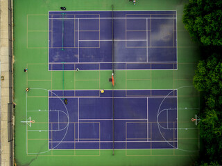 Aerial view of vividly contrasting blue and green tennis and basketball courts nestled amongst lush trees, Boston, Massachusetts, United States.