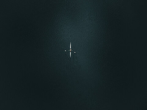 Aerial view of a lone scull cuts through the inky waters, a stark white against the deep blue canvas, Boston, Massachusetts, United States.