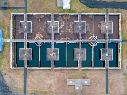 Aerial view of the stark geometry of the wastewater treatment plant, a grid of pools reflecting the sky and industrial processes, Boston, Massachusetts, United States.