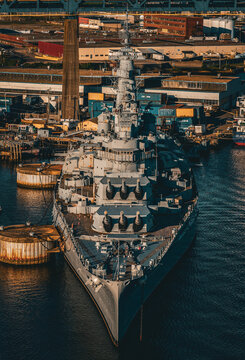 Aerial view of the Battleship Massachusetts, a steel behemoth resting in the calm waters, its weathered decks a testament to maritime history, Fall River, Massachusetts, United States.