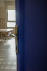 Blue Classroom Door Slightly Open with Empty Schoolroom in Background