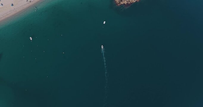 Aerial view of boats sailing on the turquoise water near a beach with rocky cliffs creating a beautiful contrast, Erchie, Amalfi Coast, Italy.