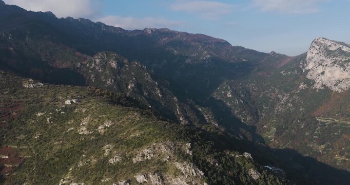 Aerial view of majestic mountains, their slopes covered in lush greenery, creating a dramatic landscape with contrasting textures, Erchie, Amalfi Coast, Italy.