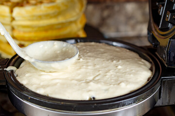 A ladle is used to carefully spread and level the thick, smooth waffle batter across the hot iron for even cooking in Waukesha County, Wisconsin.