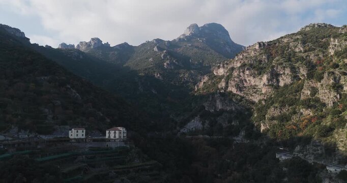 Aerial view of buildings nestled amid the rugged mountains, where lush greenery meets rocky outcrops, revealing the stunning terrain, Erchie, Amalfi Coast, Italy.