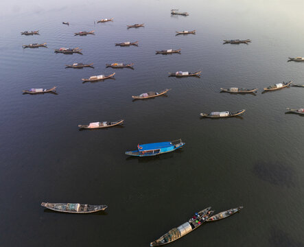 Aerial view of traditional boats with curved hulls and thatched roofs float peacefully on the shimmering Perfume River, Hue City, Hue City, Vietnam.