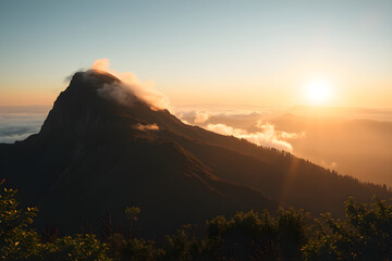 Fototapeta premium Mountain Peak Rising Above Clouds at Golden Sunrise