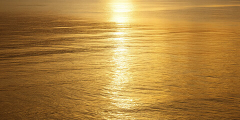 Gold water golden sunset shimmering reflection calm sea warm light serene horizon golden hour gentle ripple tranquil mood minimal nature bathe calm water warm light with shimmering reflection