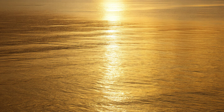 Gold water golden sunset shimmering reflection calm sea warm light serene horizon golden hour gentle ripple tranquil mood minimal nature bathe calm water warm light with shimmering reflection