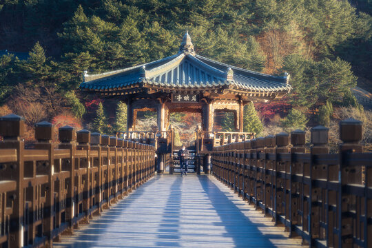 View of a traditional Korean pavilion stands at the end of a wooden bridge under the warm sun, amidst the serene landscape, Andong si, Gyeongsangbuk do, South Korea.