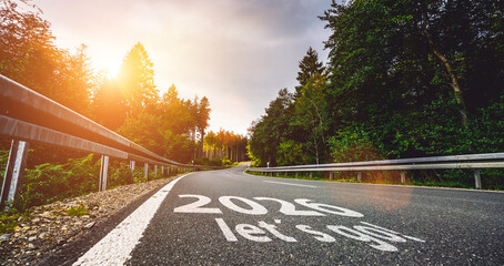New year 2026 or start straight and beginning concept. Man ride on bike and the number 2026 start written on the road at sunset with lens flare. Concept of challenge or career path, business strategy.