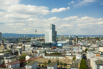 View of Frankfurt's skyline with its modern skyscrapers under a bright blue sky dotted with fluffy white clouds, casting shadows across the cityscape, Frankfurt am Main, Hessen, Germany.