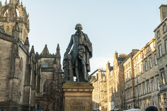 View of Adam Smith's statue stands proud against the backdrop of historic stone buildings under a bright sky, capturing a moment in time, Edinburgh, Scotland, United Kingdom.