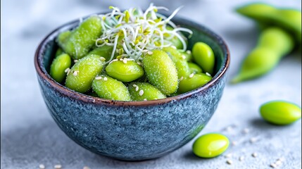 Close-up of edamame soybeans in a blue bowl, garnished with sprouts and sesame seeds