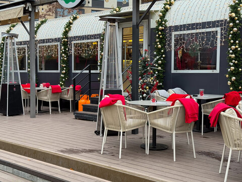 Christmas decorated cafe with heaters and garlands. Winter dining area, festive exterior and seasonal urban hospitality