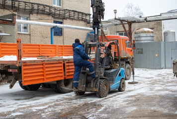 Loading a forklift onto a truck, crane, carrier, manipulator with a boom. Forklift hanging in the air on the boom of a crane © Rystemys