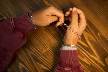 Middle aged Black woman sitting at wooden desk holding spiral hair tie in hands, wearing bracelets,...