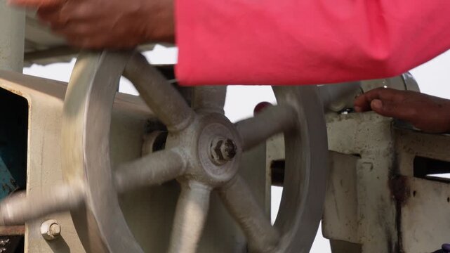 Sailor operating large steering wheel to change the direction of a ship