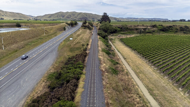 Aerial view of State Highway 1 running parallel to a railway track, bordered by vineyards under a cloudy sky, Seddon, Marlborough Region, New Zealand.