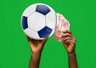 A pair of black african hands holds a blue and white soccer ball and Ghana Cedi banknotes against a green background