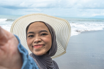 a woman wearing a hijab is on holiday at the beach