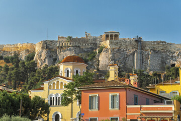 Panoramic view of the Acropolis in Athens, Greece with the Parthenon prominently positioned atop a rocky hill. Below the ancient monument are colorful buildings including a church with a red dome © hectorchristiaen