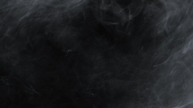A heavy, dense cloud of white smoke or fog rolls slowly from the top left corner, creating a thick, atmospheric texture on a black background
