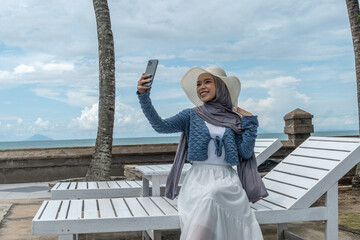 a young woman holding a cell phone in a hotel with a beach view while on vacation, perfect for vacation promotions and social media