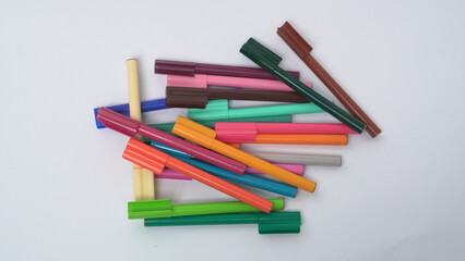 Obraz premium Close up of various multi colored markers scattered randomly on a white background, useful for stationery and education themes