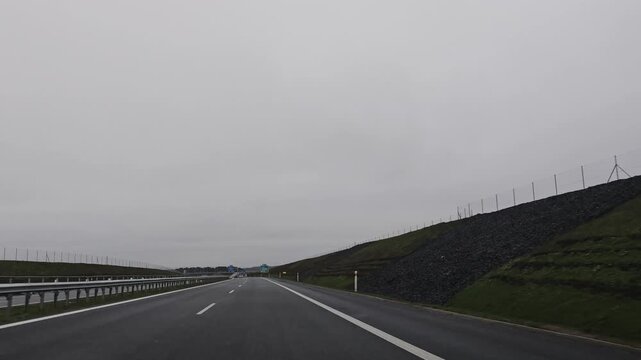 Driving on a highway from Karlovy Vary to Prague during winter, surrounded by a bleak, overcast landscape and patches of snow along the roadside.